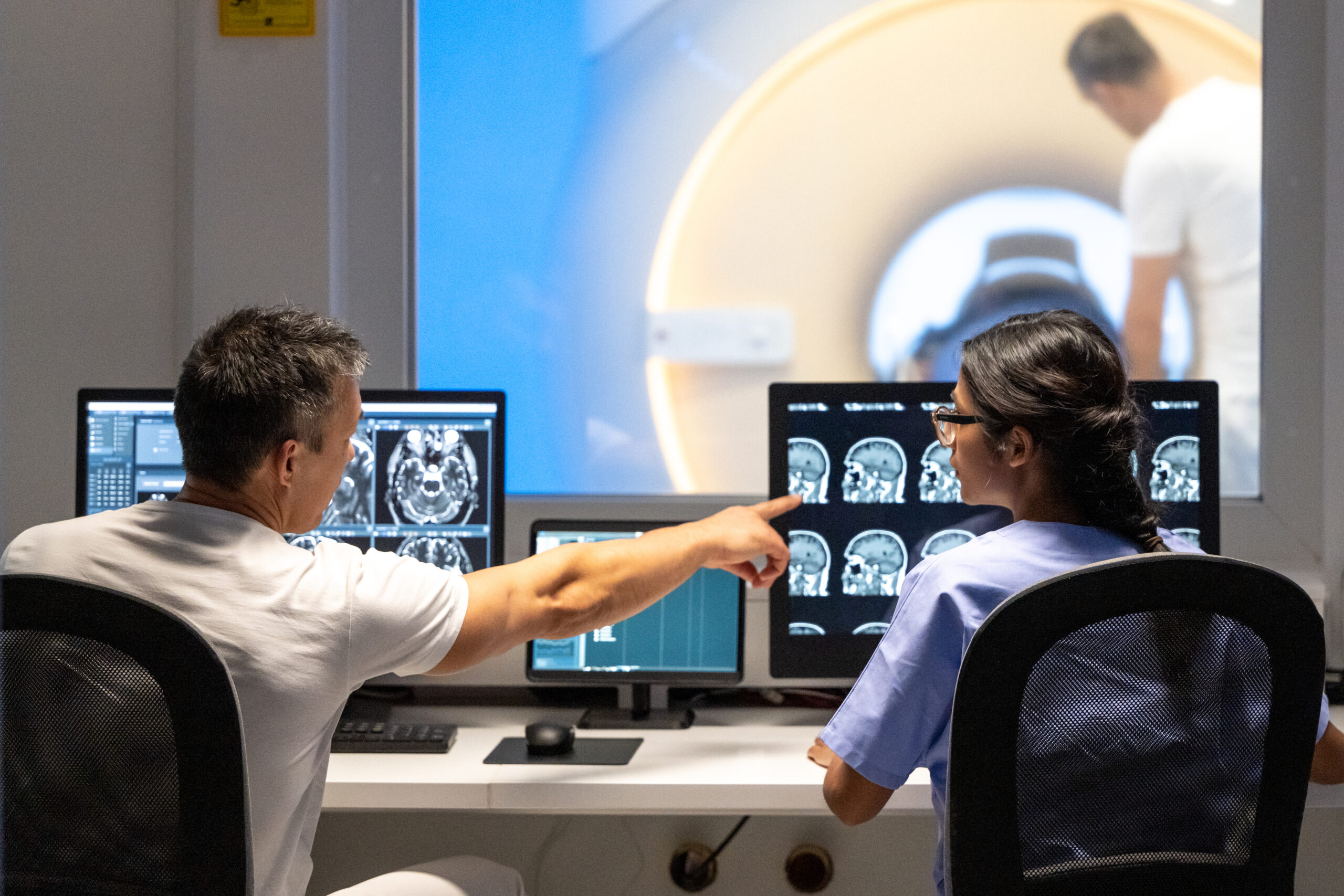 Back view of two doctors analyzing MRI scan results. Man pointing at images on monitor screen. 1314783937 3869x2580 scaled